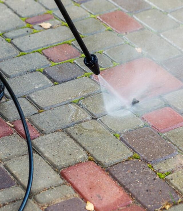 Betonklinkers met groene aanslag worden gereinigd met een hogedrukspuit
